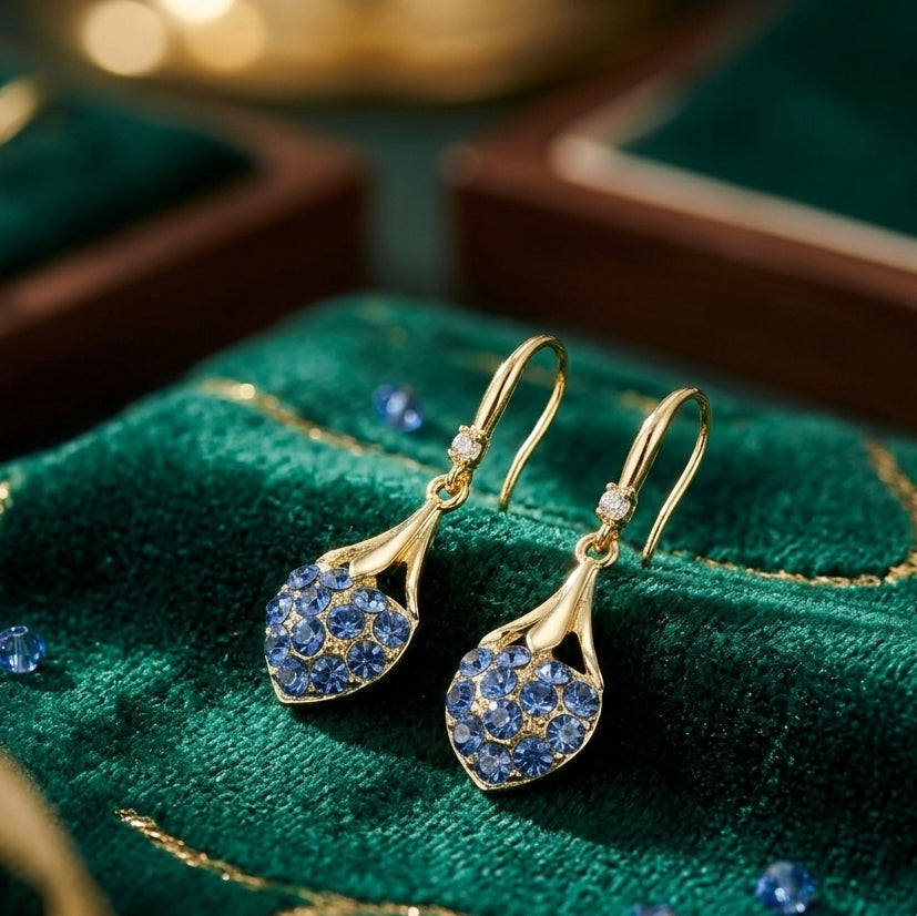 Blue crystal heart drop earrings gold tone on green velvet luxury display