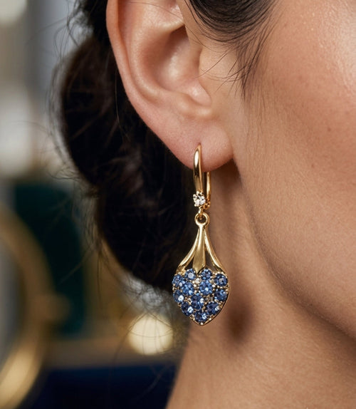 Model wearing blue crystal heart drop earrings gold tone close up side view